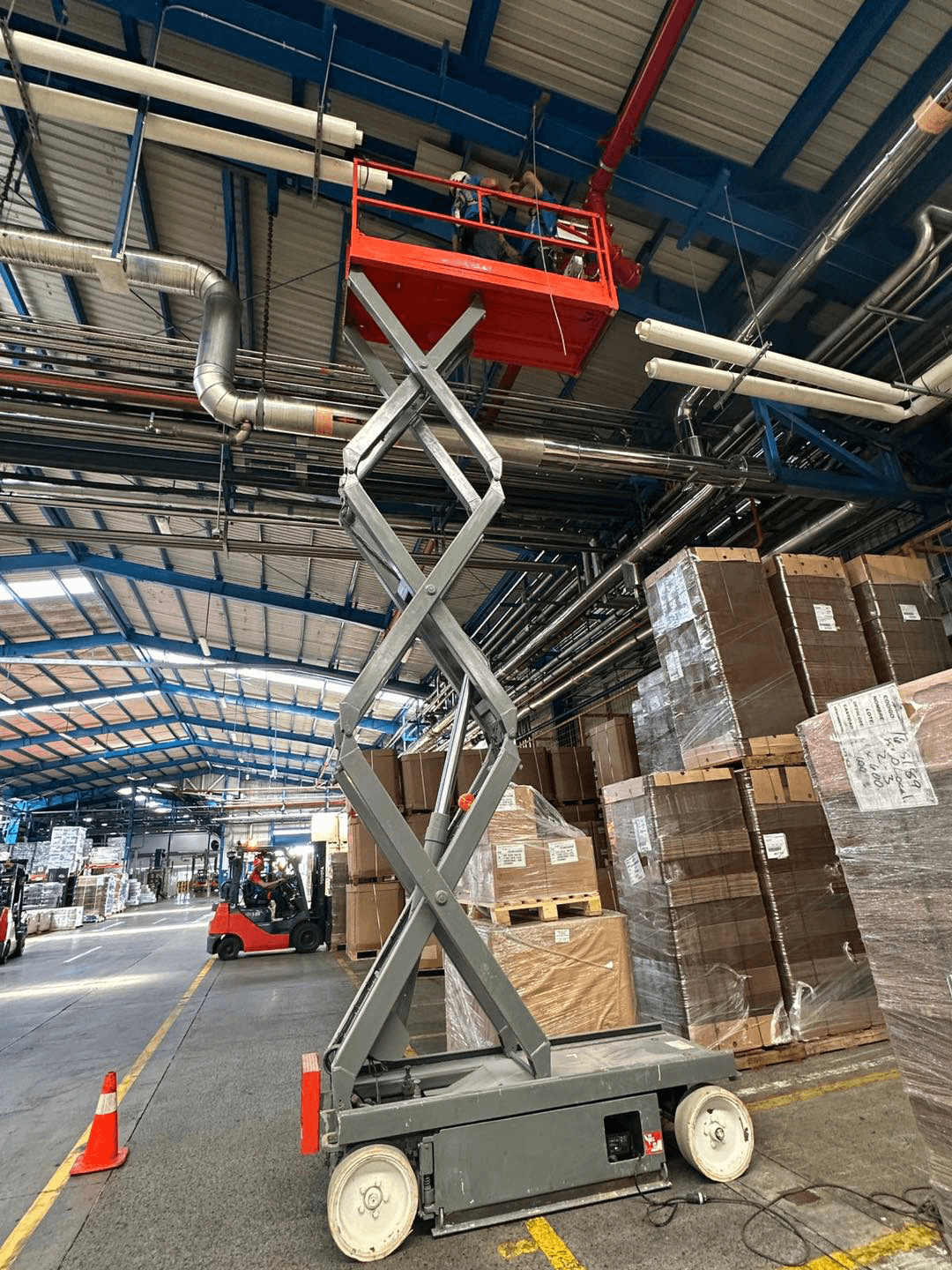 Operarios trabajando en altura sobre scissor lift en planta industrial